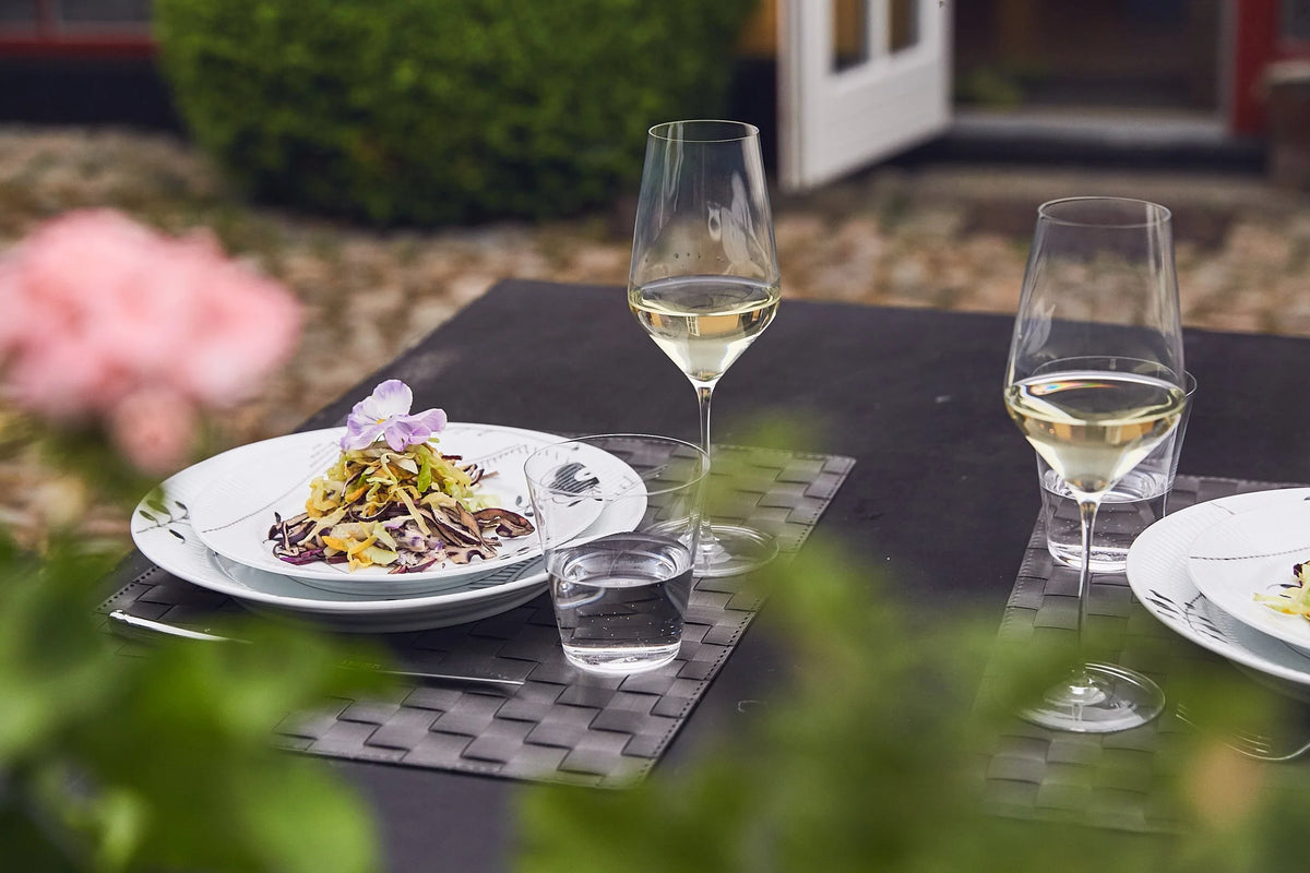 Outdoor restaurant table with plated dishes and Zalto glassware
