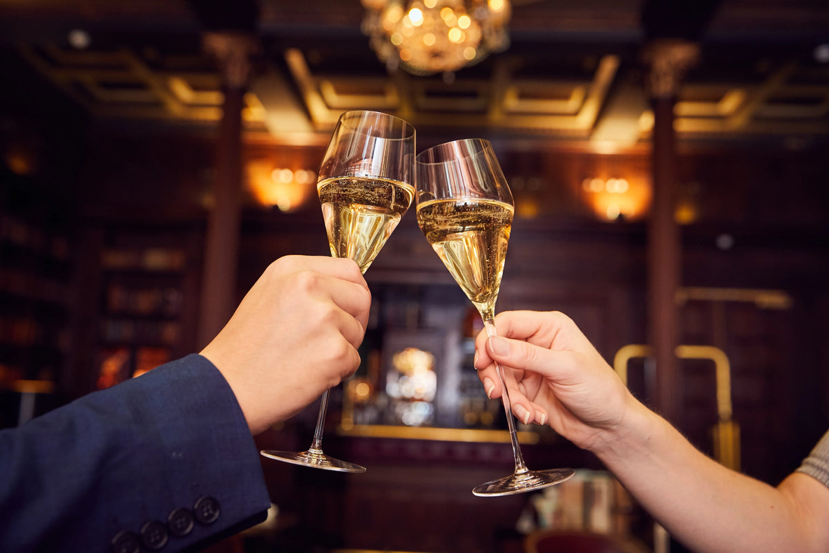 Two Zalto Champagne glasses raised in a toast in a bar
