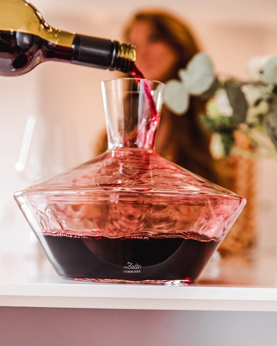 Red wine poured from a bottle into a Zalto Mystique decanter
