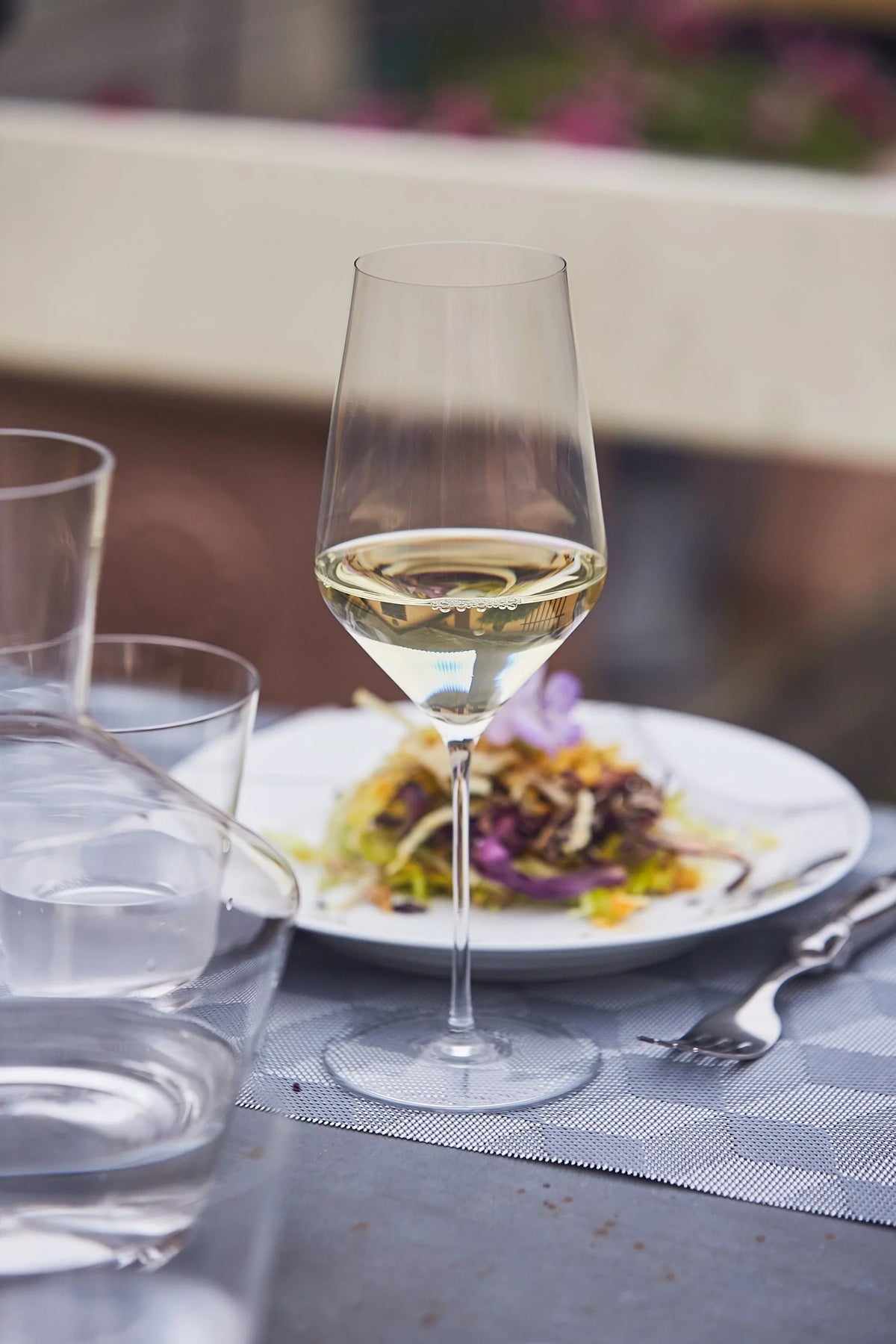Zalto White Wine glass of white wine beside a plated starter on a restaurant table