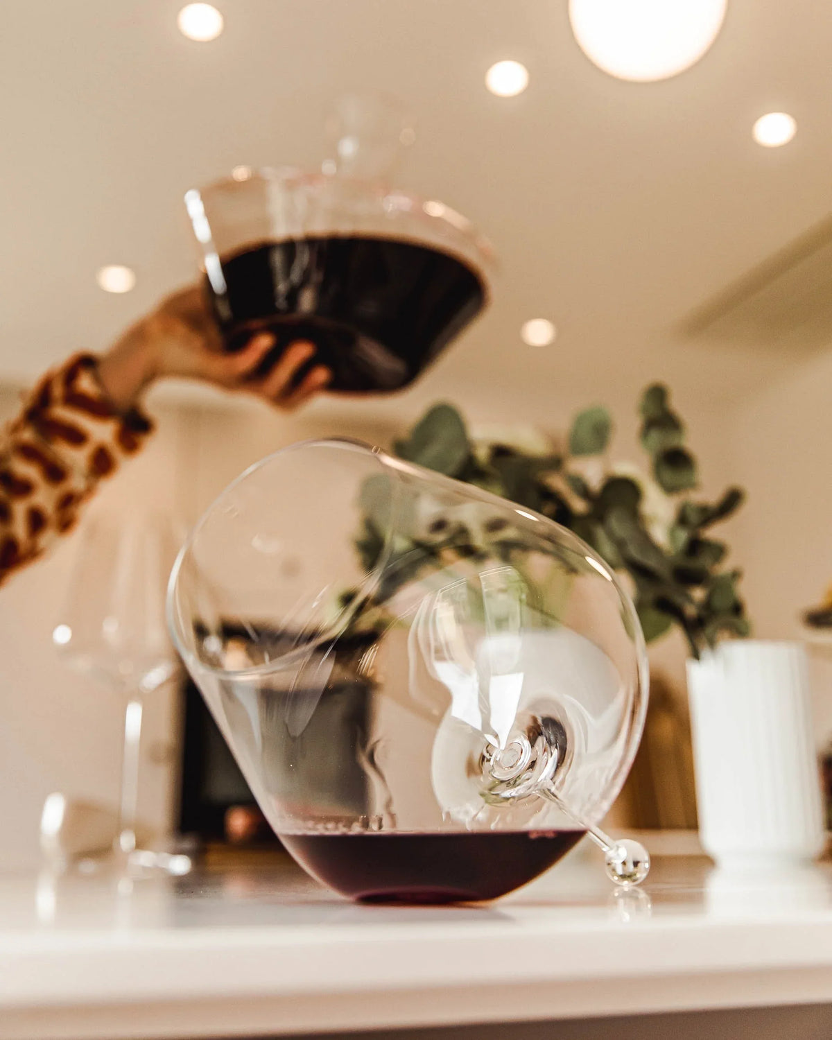 Red wine being poured into a Zalto Gravitas Omega glass on a kitchen counter